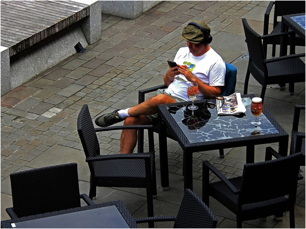 Man sitting at table with beer and mobile phone.